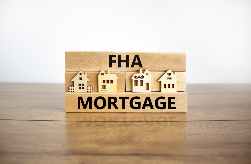 FHA mortgage symbol. Wooden blocks form the words 'FHA mortgage', miniature houses, wooden table. Beautiful white background, copy space. Business and FHA mortgage concept.